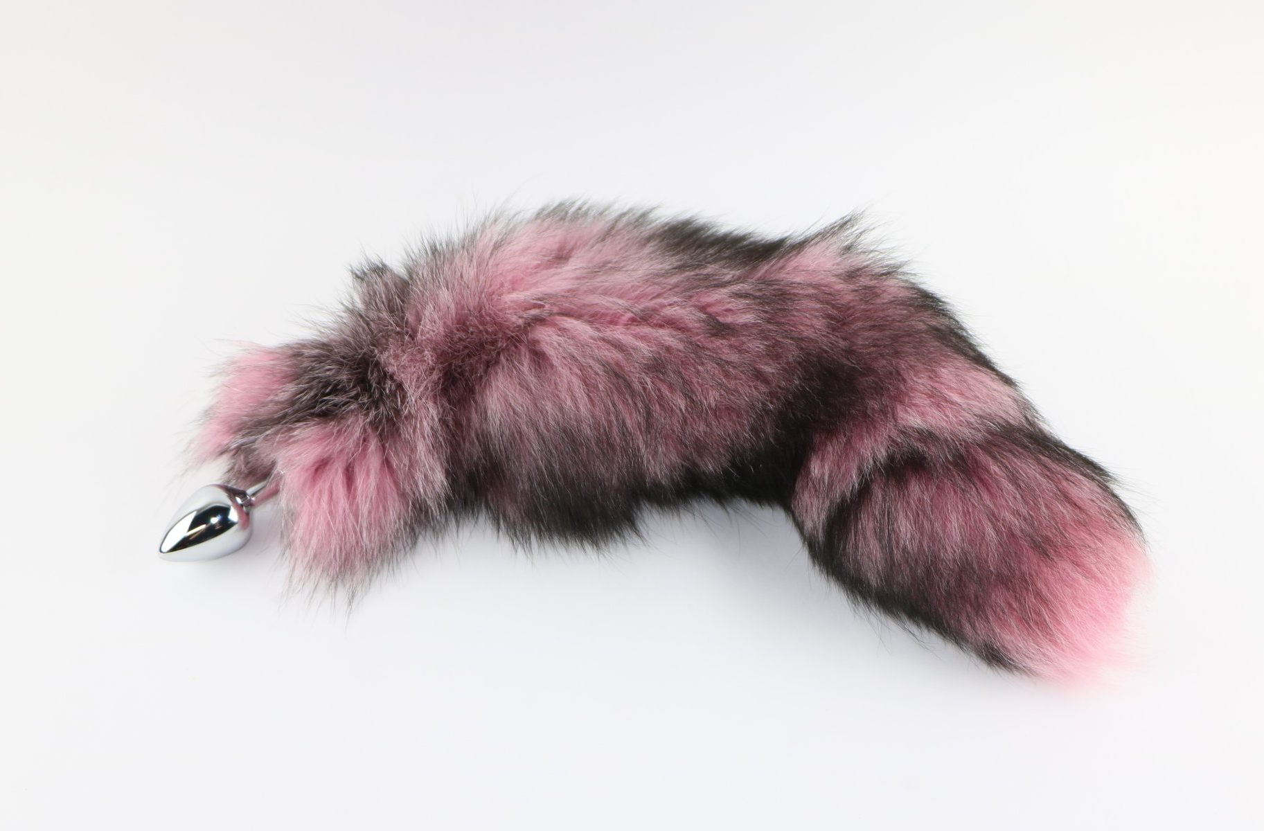 Picture of indigo fox tail dyed light pink from Spank Academy website. Tail is pink with black accents and attached to a stainless steel plug.