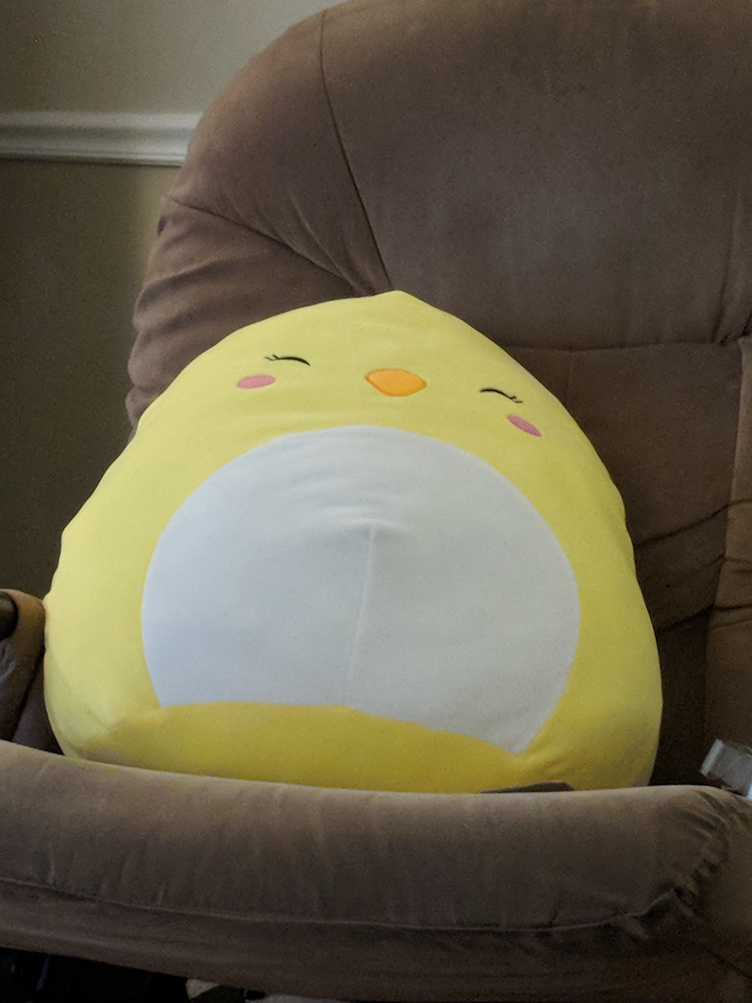 Giant chicken squishmallow on a chair