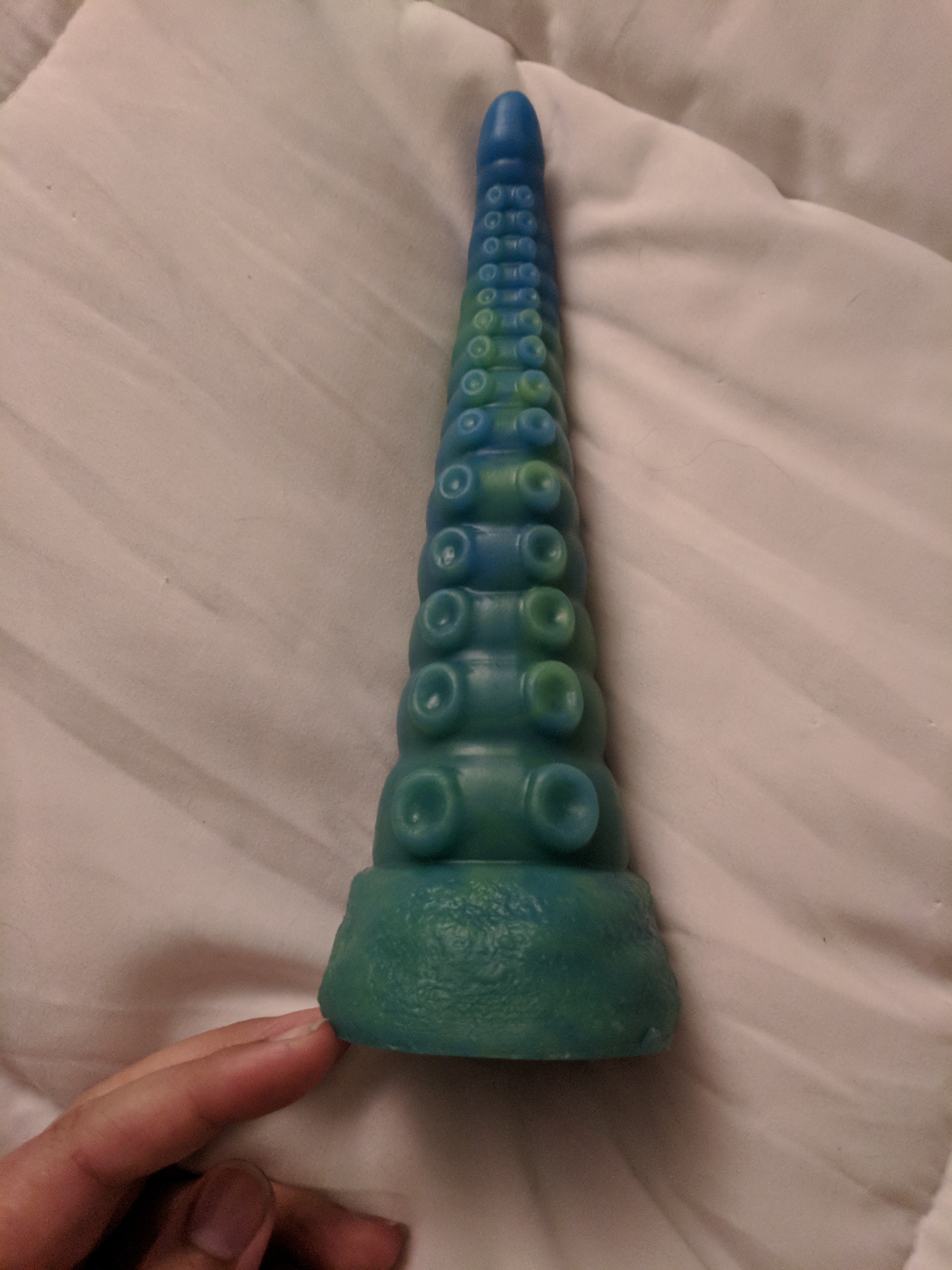 Tentacle dildo on bed at a different angle, with suction cups facing up toward the camera