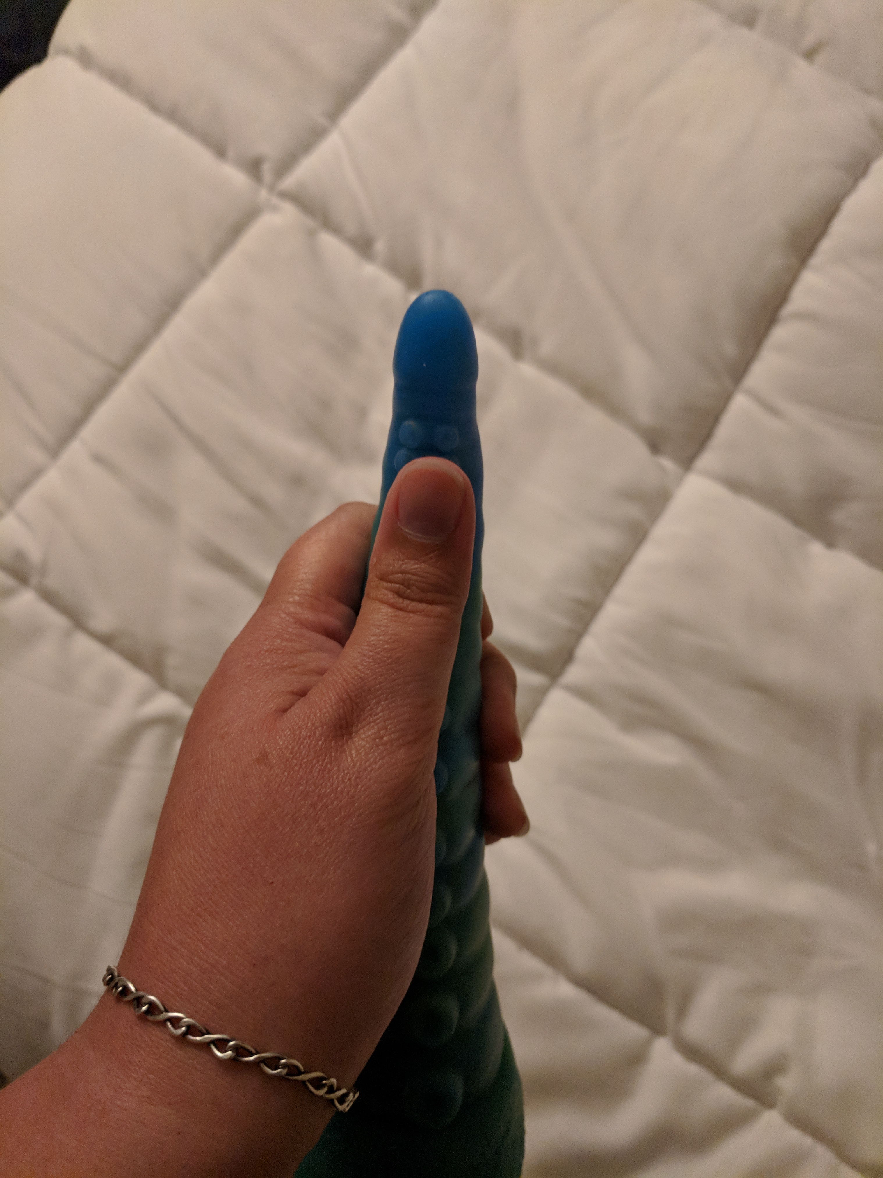 Tentacle dildo in hand, with thumb against tip, showing the tip as wide as a thumb