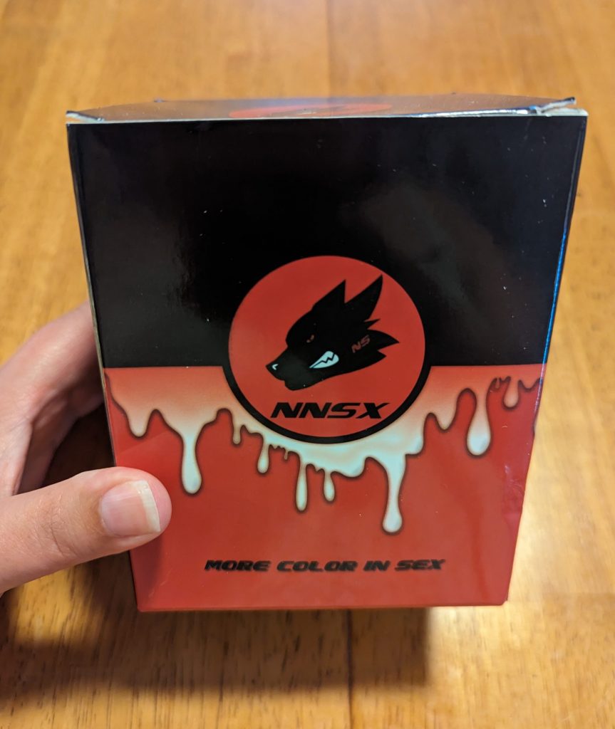 Paperboard box with a cartoon wolf head. Box is black and orange and says "More color in sex."