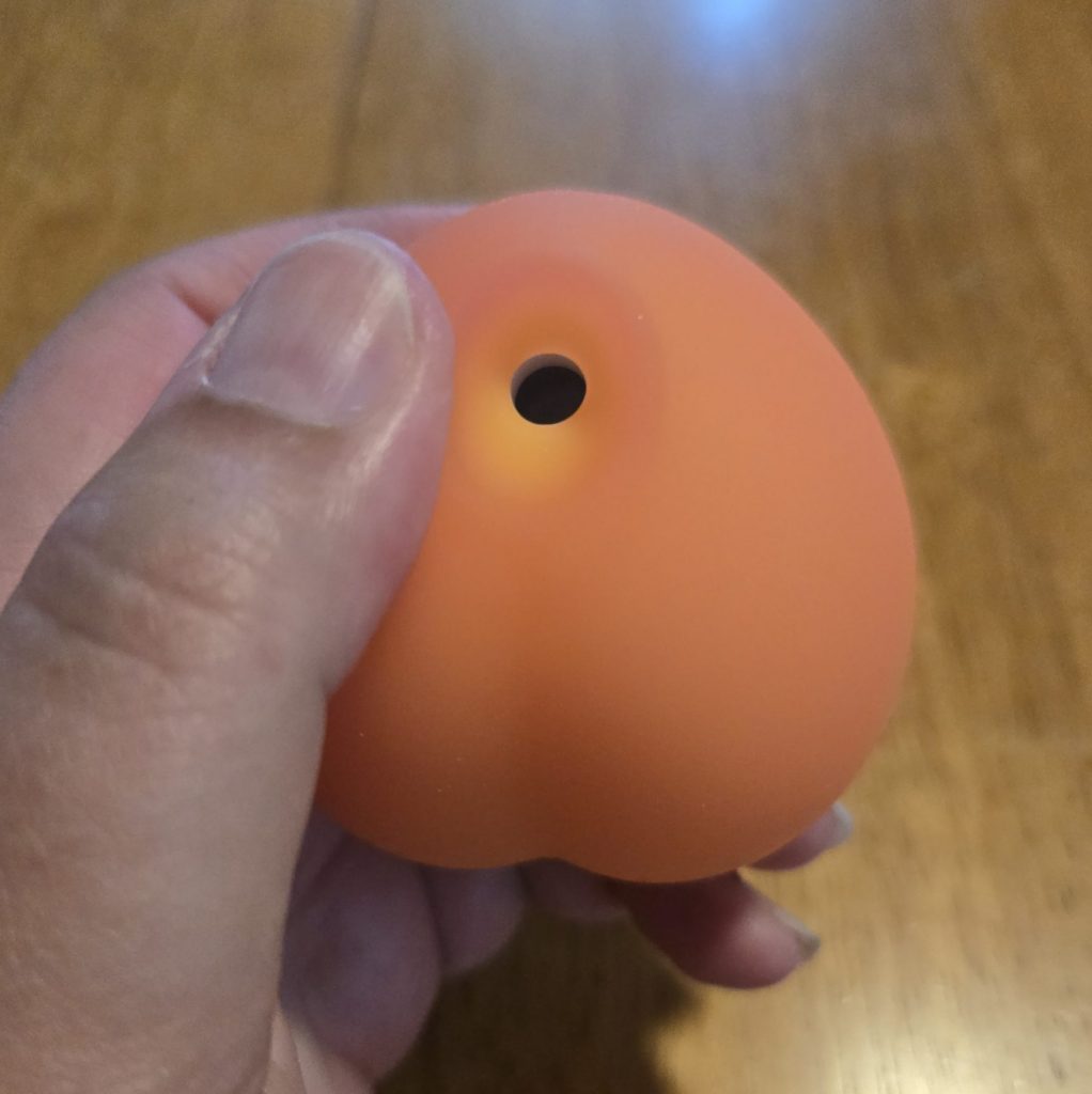 Peach with thumb to show hole size